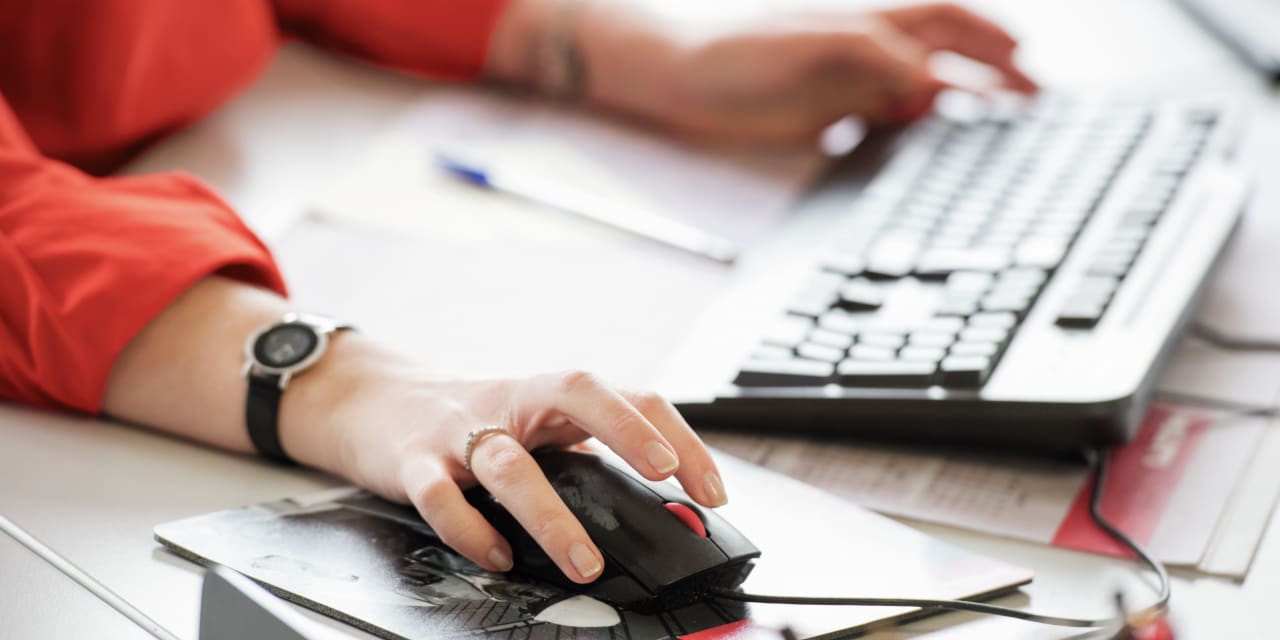 Person sidder foran computer med en mus i hånden og taster på tastetur