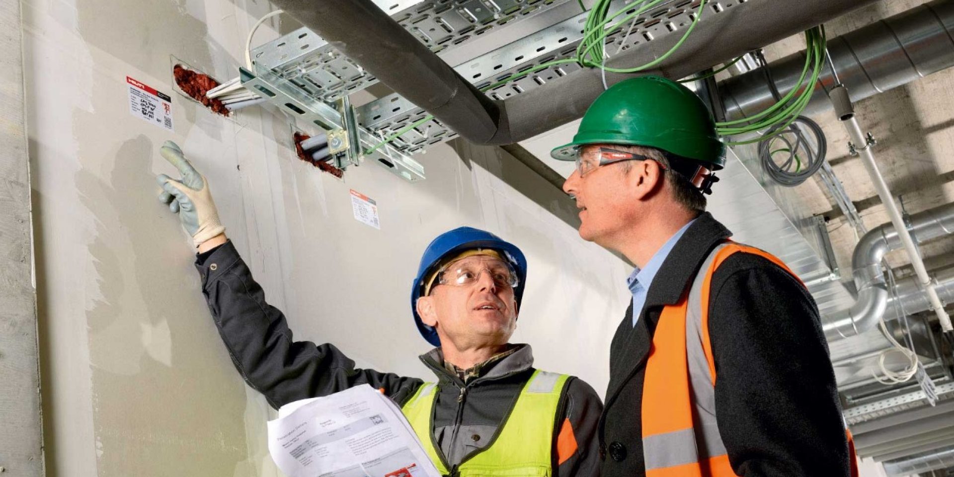 To personer ser på brandsikringsmærkat på en betonvæg