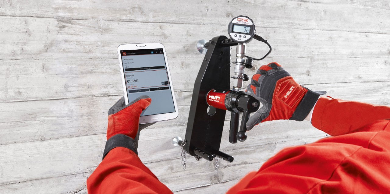 Person ser på en trækprøve og Hilti app på en telefon
