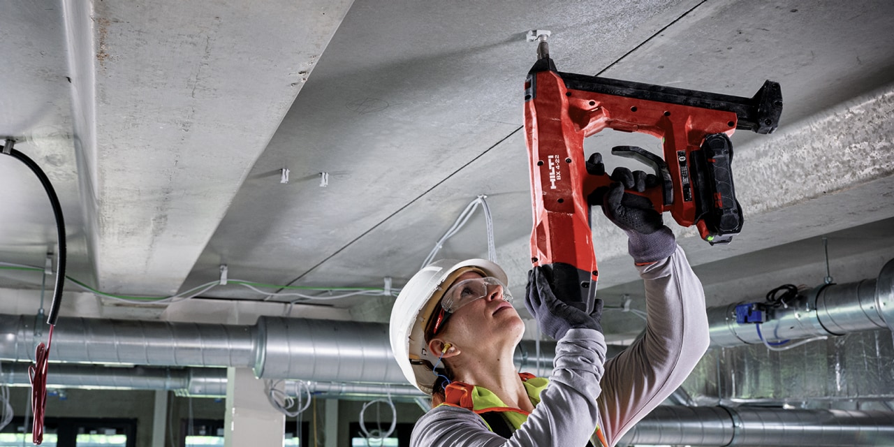 arbejder borer huller i loften med en BX3 boltepistol