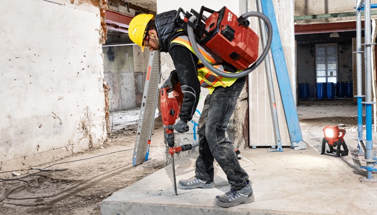 En arbejder som borer huller i betonflade med Hilti borehammer og støvsuger