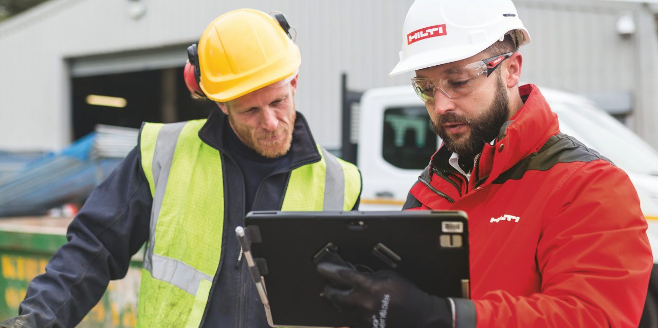 To personer ser på en tablet på en byggeplads